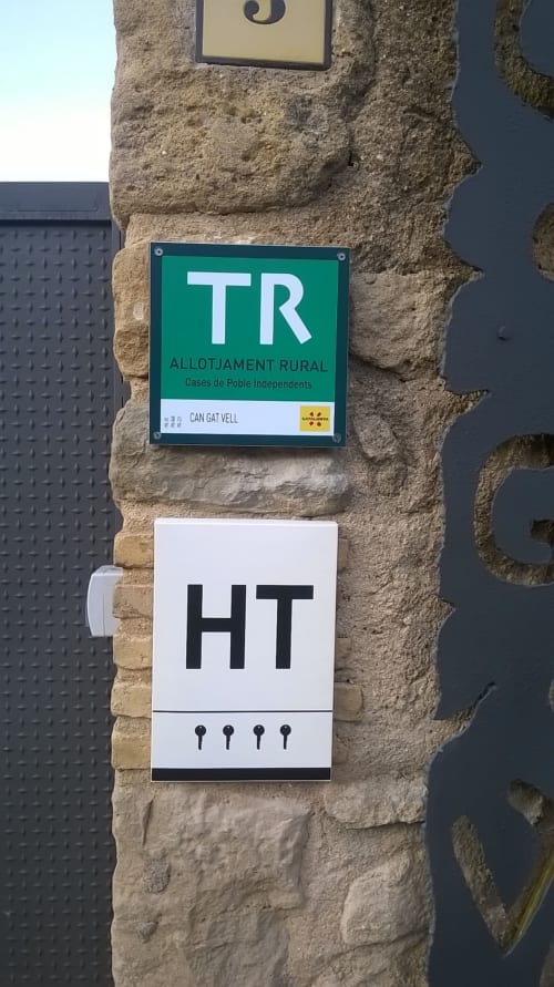 Señales de alojamiento rural TR para Can Gat Vell, casa rural en Girona, Empordà-Catalunya, montadas en pared de piedra