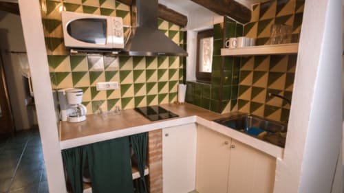 Cocina compacta en Can Gat Vell B&B en Girona con azulejos geométricos, encimeras de madera y electrodomésticos modernos