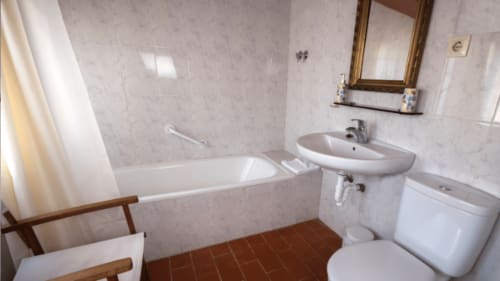 Cuarto de baño de Can Gat Vell B&B en Girona con bañera, lavabo, inodoro y azulejos de terracota
