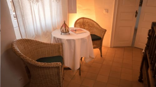 Acogedor rincón de estar en Can Gat Vell B&B en Girona con sillas de mimbre, mesa redonda e iluminación cálida