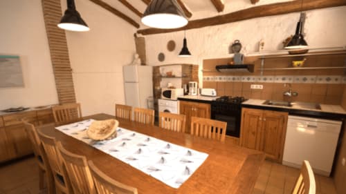 Acogedora zona de cocina-comedor con vigas rústicas en el B&B Can Gat Vell de Girona, pan sobre la mesa