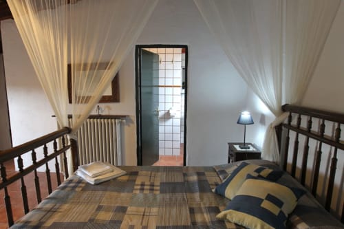 Acogedor dormitorio en la casa rural Can Gat Vell en Girona, España con camas de madera y cortinas translúcidas