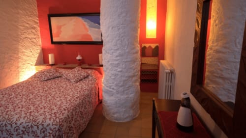 Acogedora habitación en Can Gat Vell B&B en Girona con acentos rojos, columna de piedra blanca e iluminación ambiental cálida