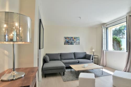 Salon moderne de la villa Maison Grand Large avec canapé gris, table en bois et vue sur le jardin