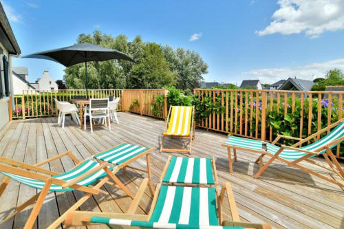 Terrasse de la villa Maison Grand Large avec transats rayés, parasol et vue sur le jardin à Saint-Cast-le-Guildo
