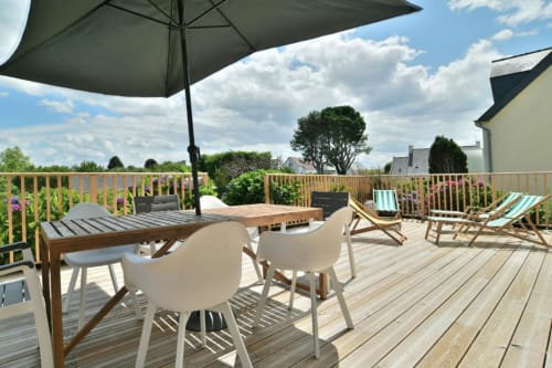 Terrasse ensoleillée de la villa Maison Grand Large avec table de repas, parasol et vue sur le jardin à Saint-Cast-le-Guildo