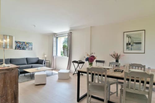 Salon moderne de la Maison Grand Large avec table à manger, canapé bleu et vue sur le jardin par les portes-fenêtres