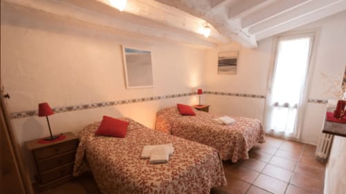 Dormitorio rústico en la Casa Rural Can Gat Vell en Girona con tres camas, almohadas rojas y vigas de madera