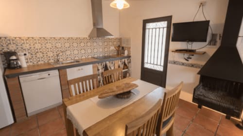 Cocina y comedor moderno en el alojamiento Can Gat Vell B&B en Girona, con mesa de madera, gabinetes blancos y estilo contemporáneo