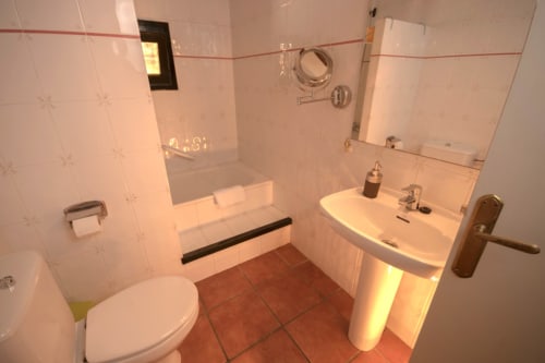 Baño con azulejos blancos, lavabo, inodoro y ducha en la casa de campo Can Gat Vell, Girona