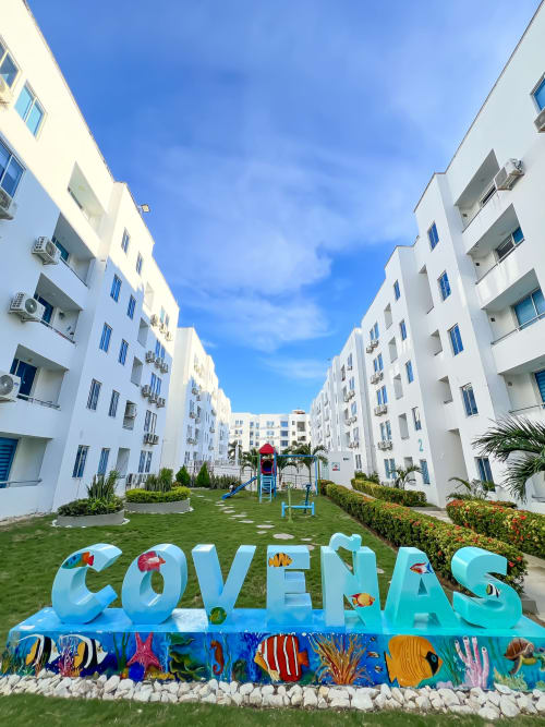 Resort frente al mar en Coveñas con edificios blancos, patio verde, área infantil y señalética colorida con tema oceánico