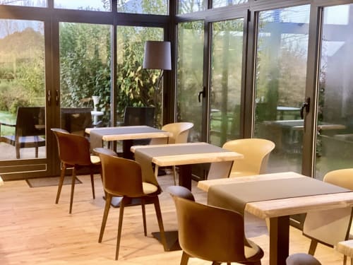 Salle à manger moderne de l'Hôtel Saint Roch avec tables en bois, chaises beige et baies vitrées surplombant les jardins