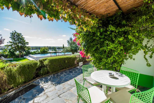 Terraço sombreado com cadeiras verdes com vista para a piscina e o rio Douro na vila Casas de Juromenha, Portugal