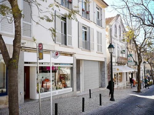Fachada do edifício de apartamentos Casas de Juromenha em Juromenha, Portugal, com loja branca em rua de pedestres.