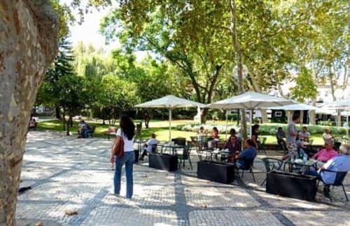 Pátio externo de Casas de Juromenha, Juromenha, com áreas de descanso sombreadas e hóspedes apreciando o espaço verde do jardim