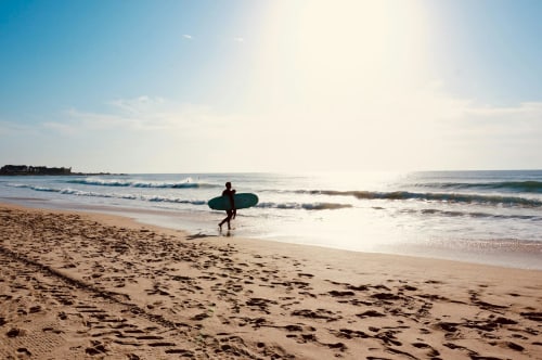 Surfista com prancha entrando nas ondas da praia de Matosinhos perto de Casa Da Avó Ilda