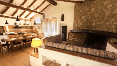 Sala de estar de la casa rural Can Gat Vell en Girona con chimenea, comedor y decoración rústica moderna
