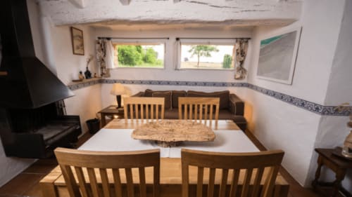 Comedor de la casa rural Can Gat Vell en Girona con mesa de madera, sillas y vistas al campo