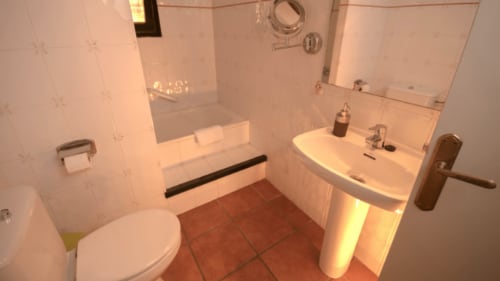 Baño limpio con azulejos blancos, lavabo, inodoro y ducha en el Can Gat Vell B&B en Girona, Cataluña