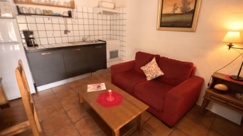 Acogedor estudio en Girona con sofá rojo, cocina americana e iluminación cálida en Can Gat Vell