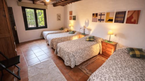 Amplia habitación en Can Gat Vell B&B en Girona con múltiples camas e iluminación cálida
