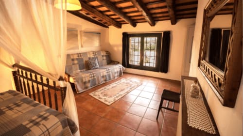 Habitación rústica en Can Gat Vell B&B de Girona con vigas de madera, suelos de terracota y mobiliario tradicional