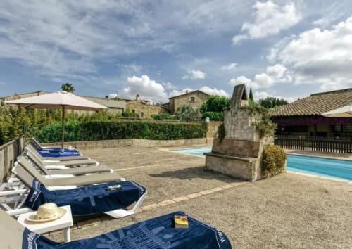Casa rural catalana con piscina, tumbonas, estructuras de piedra y jardines cerca de Girona