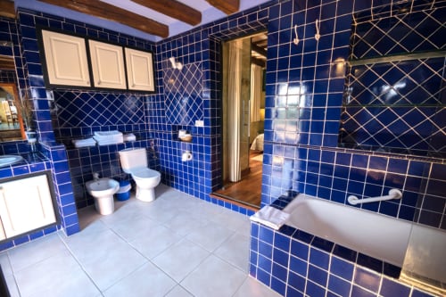 Baño de lujo con azulejos azules, bañera, inodoro y lavamanos en la casa rural Can Gat Vell en Girona, España