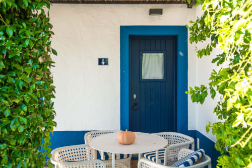 Porta azul de entrada para a vila Casas de Juromenha com terraço externo e vegetação verde exuberante, Portugal