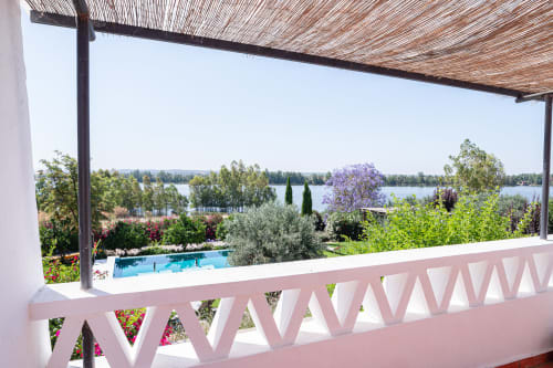Terraço com corrimão rosa com vista para a piscina, jardins e rio na villa Casas de Juromenha em Portugal