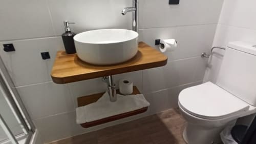 Baño moderno en el alojamiento Can Gat Vell B&B en Girona con lavabo tipo vasija sobre mueble de madera y inodoro blanco