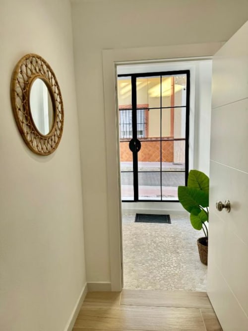 Pasillo moderno de apartamento en Nerja Holiday Homes con espejo tejido, planta macetada y vista a las puertas de la terraza