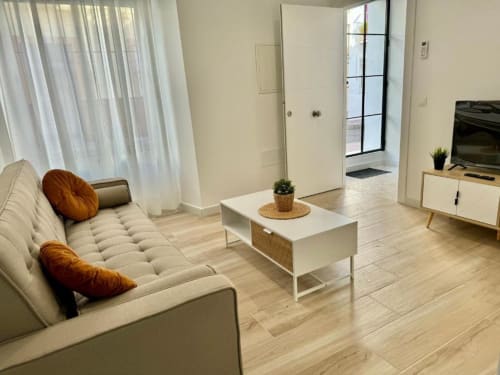 Salón de apartamento en Nerja moderno con sofá crema, detalles de madera y decoración minimalista