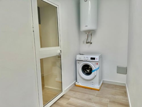 Lavadero moderno en apartamento Nerja Holiday Homes con lavadora blanca, calentador de agua y suelo de madera