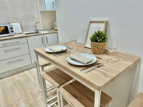 Moderna zona de cocina-comedor en apartamento de Nerja Holiday Homes con mesa de madera, cubiertos y decoración con plantas