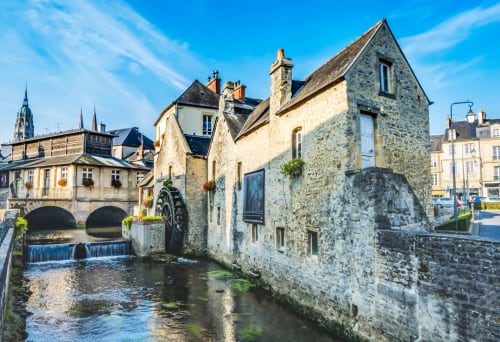 Bâtiments historiques en pierre le long d'un canal à Bayeux, France, où se situe l'hôtel Le 58 Bayeux