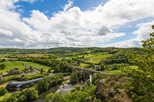 Vue pittoresque de la vallée près de Bayeux avec viaduc historique, rivière, champs verts et ciel nuageux