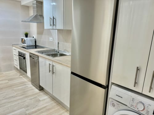 Cocina moderna blanca del apartamento Nerja Holiday Homes con electrodomésticos de acero inoxidable, fregadero, placa de cocción y refrigerador