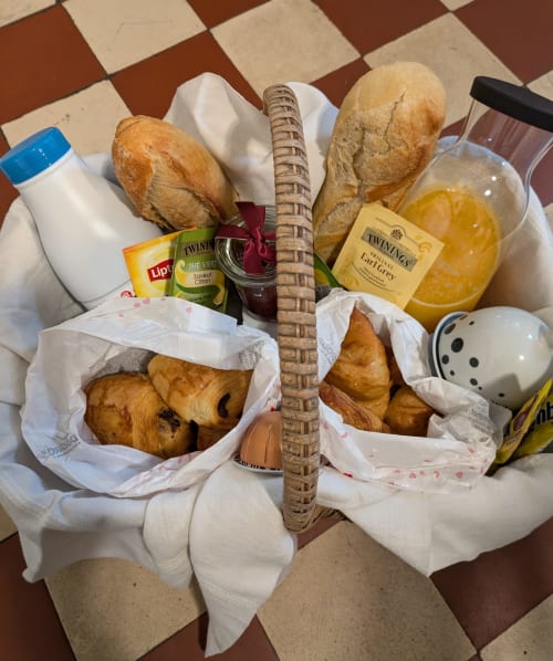Continental breakfast basket at Manoir Saint Joseph villa in Sens with fresh baguettes, pastries, tea, juice and bread rolls