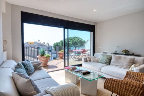 Sala de estar moderna del hotel Finques Garcia Enrich en Palafrugell con terraza, sofá, mesa de cristal y balcón con vista al mar