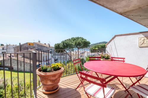Mobiliario de patio rojo y maceta de terracota en terraza con vistas a Palafrugell y el mar