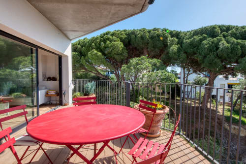 Mesa y sillas rojas en la terraza soleada del hotel Finques Garcia Enrich en Palafrugell, con vistas a los árboles