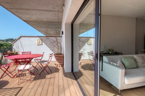 Terraza soleada de Finques Garcia Enrich en Palafrugell con muebles rojos, tarima de madera y acceso a vistas al mar