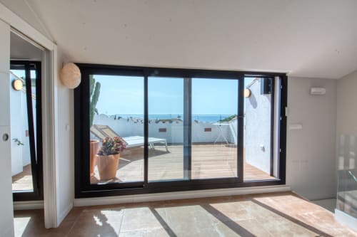 Habitación moderna y luminosa con puertas de cristal de marco negro que abren a una terraza con vistas al mar en Finques Garcia Enrich, Palafrugell