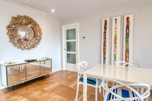 Comedor moderno en Finques Garcia Enrich en Palafrugell con mesa de madera, sillas blancas y espejo decorativo