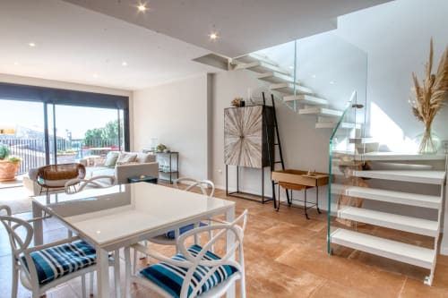 Moderna área de estar diáfana en Finques Garcia Enrich de Palafrugell con mesa de comedor, escalera y acceso a terraza