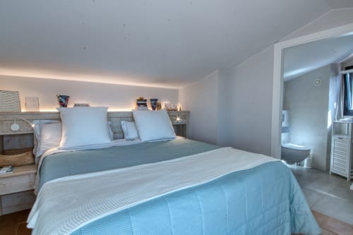 Dormitorio moderno en Finques Garcia Enrich, Palafrugell, con cama queen, iluminación ambiental y baño en suite