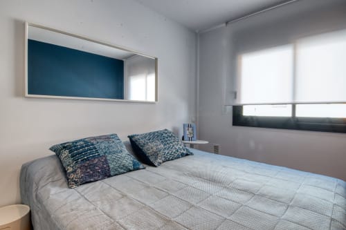Dormitorio moderno en el hotel Finques Garcia Enrich de Palafrugell con pared azul, cama queen, almohadas estampadas y luz natural