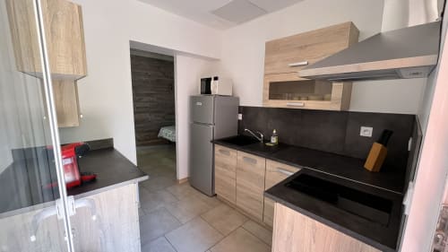 Cuisine moderne avec plan de travail noir et mobilier en bois à la villa Le Maquis Plage à Poggio-Mezzana