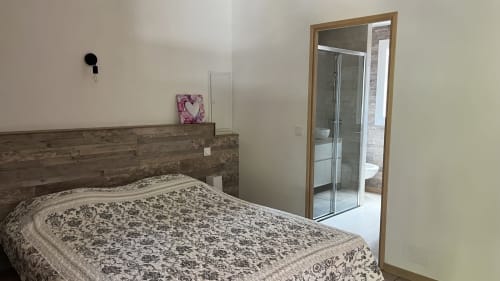 Chambre de la villa Le Maquis Plage avec tête de lit en bois, literie motifs et salle de bains attenante